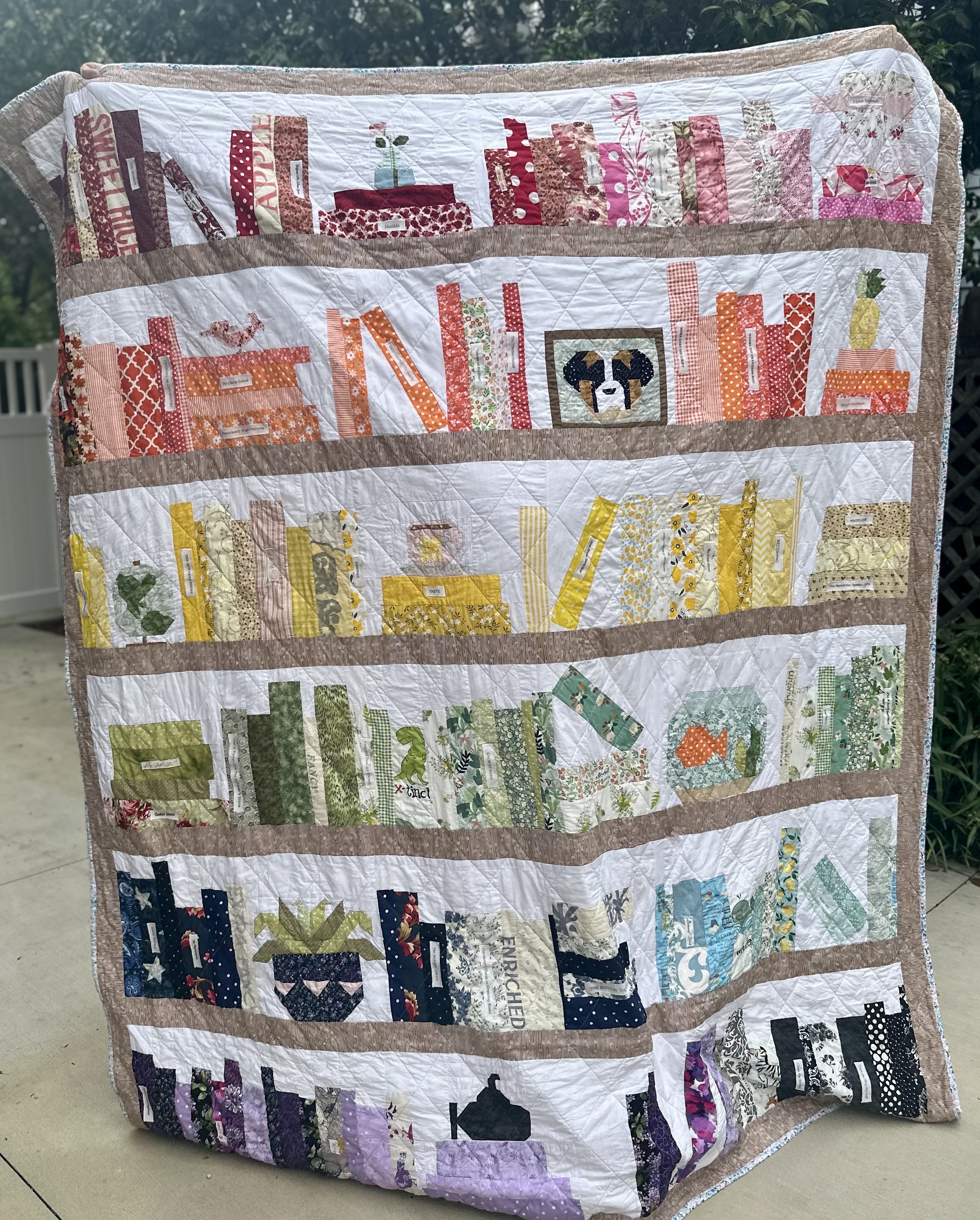 photo of bookshelf quilt, with personal touches like pictures and book spines